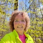 kvinde i lyserød løbetrøje og gul løbejakke i bøgeskov