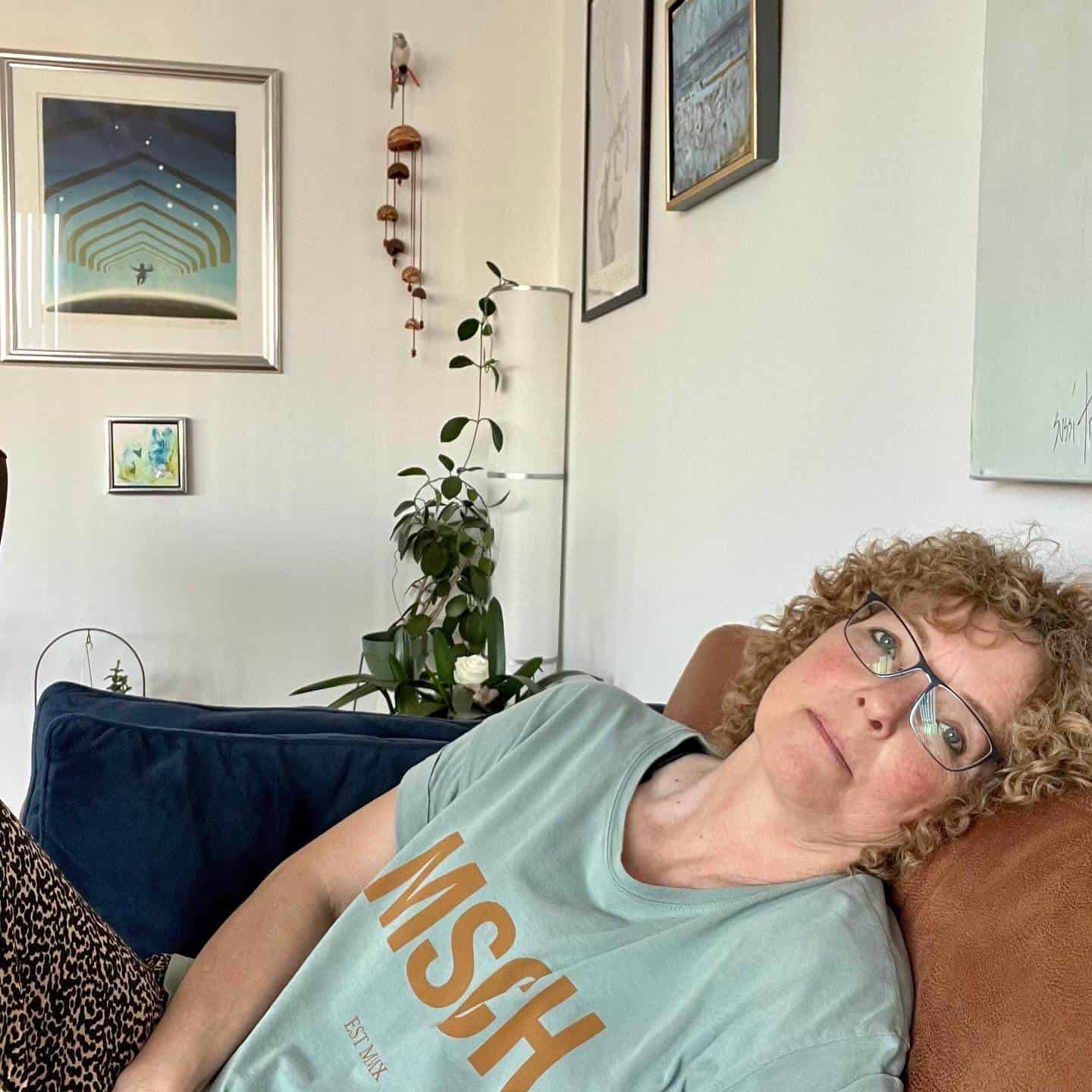 Træt og stressramt kvinde i grøn t-shirt på cognacfarvet sofa
